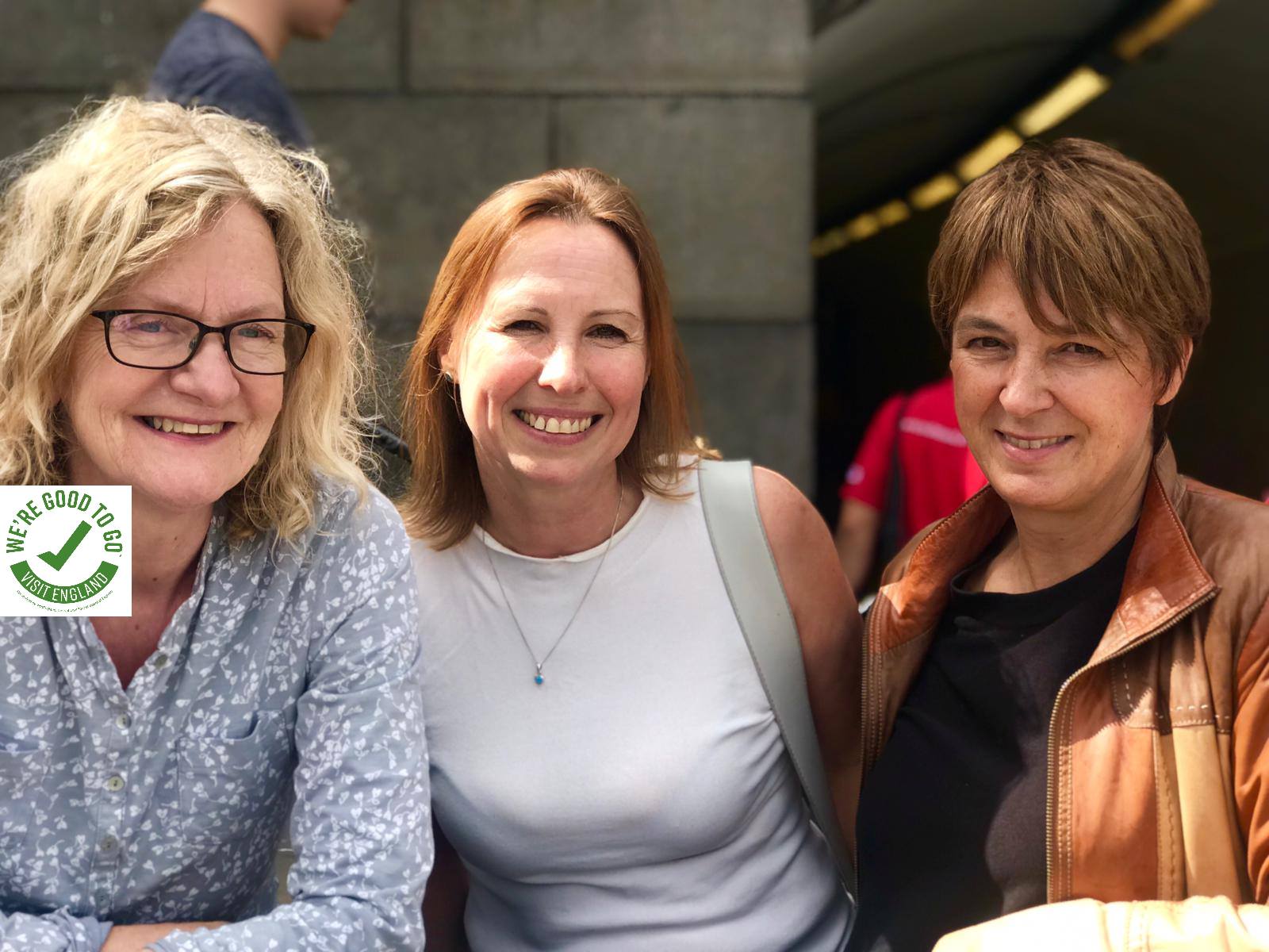 Three women posing for a picture, smiling happily.